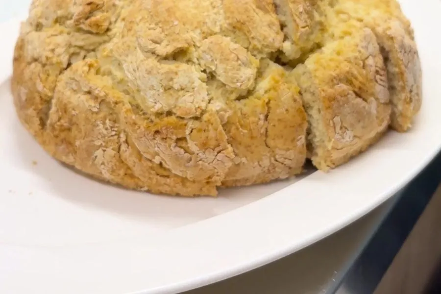 A golden, freshly baked damper on a white serving platter