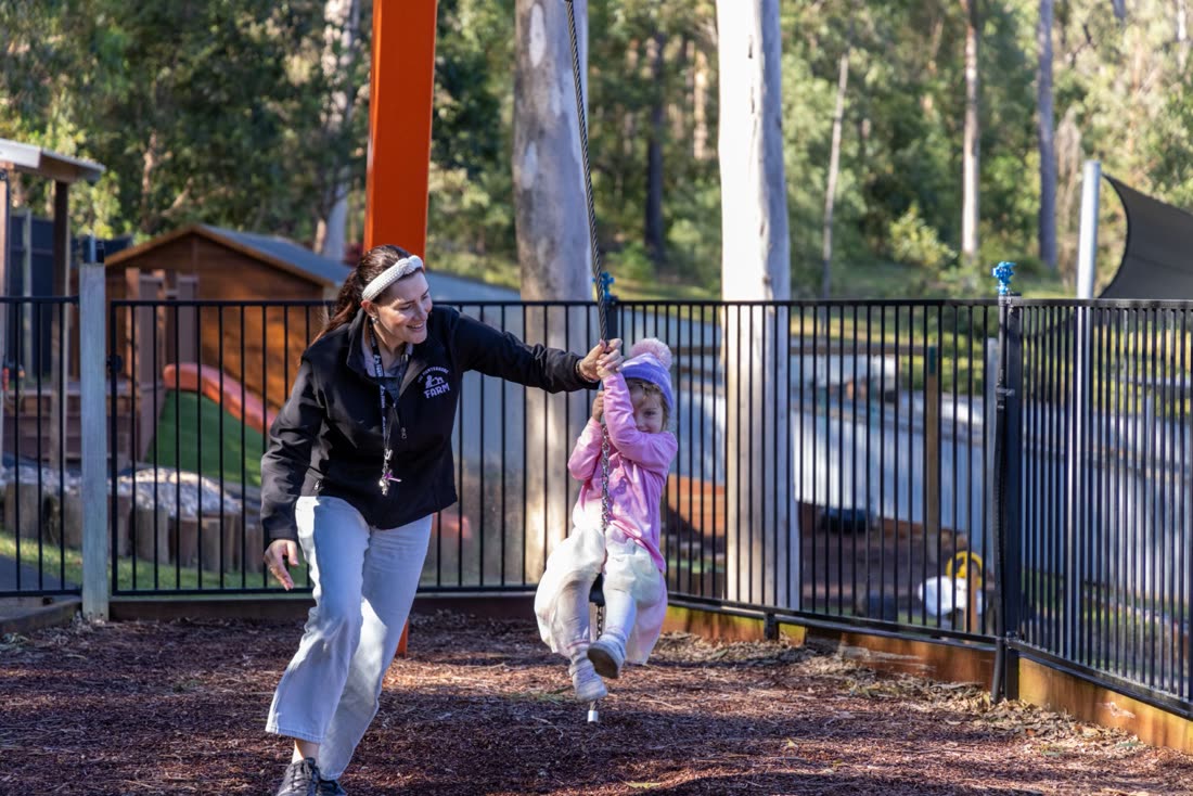 An educator playing outdoors with children