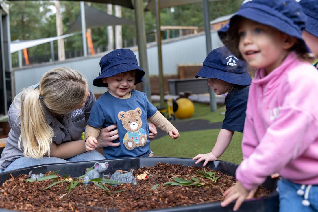 Children and an educator at the sensory play tub