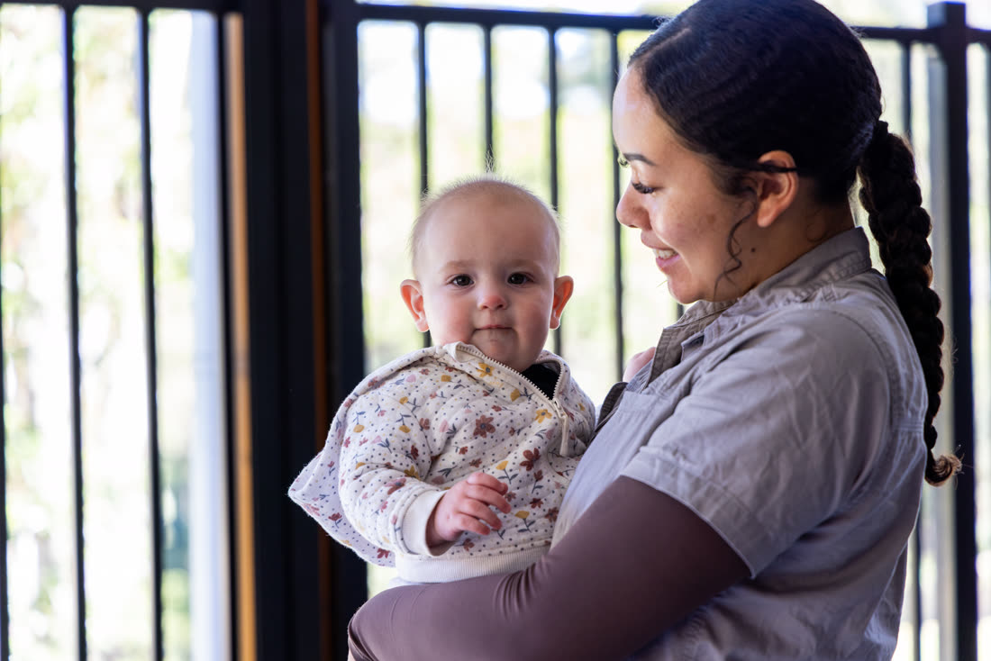 An educator holding a baby by the window