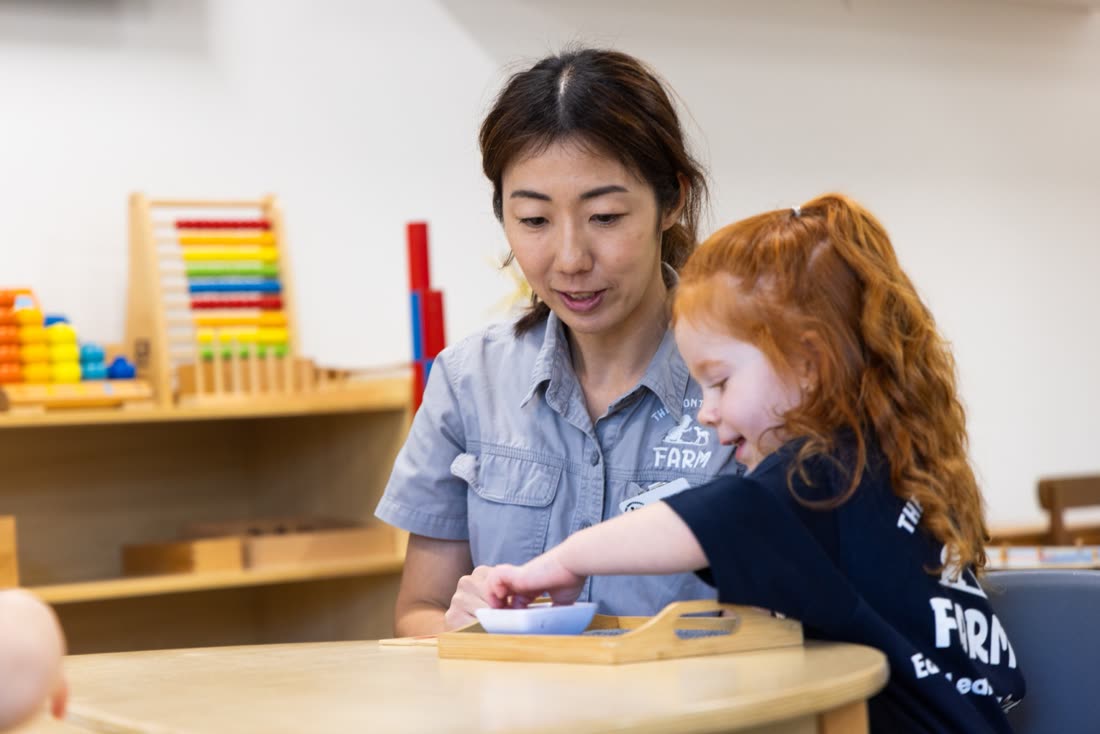 An educator and child working with Montessori materials at a table